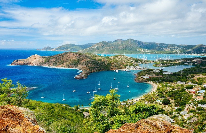 Panoramic view of English Harbour in Antigua from Shirley Heights with rolling green hills, beaches and yachts scattered across the water.