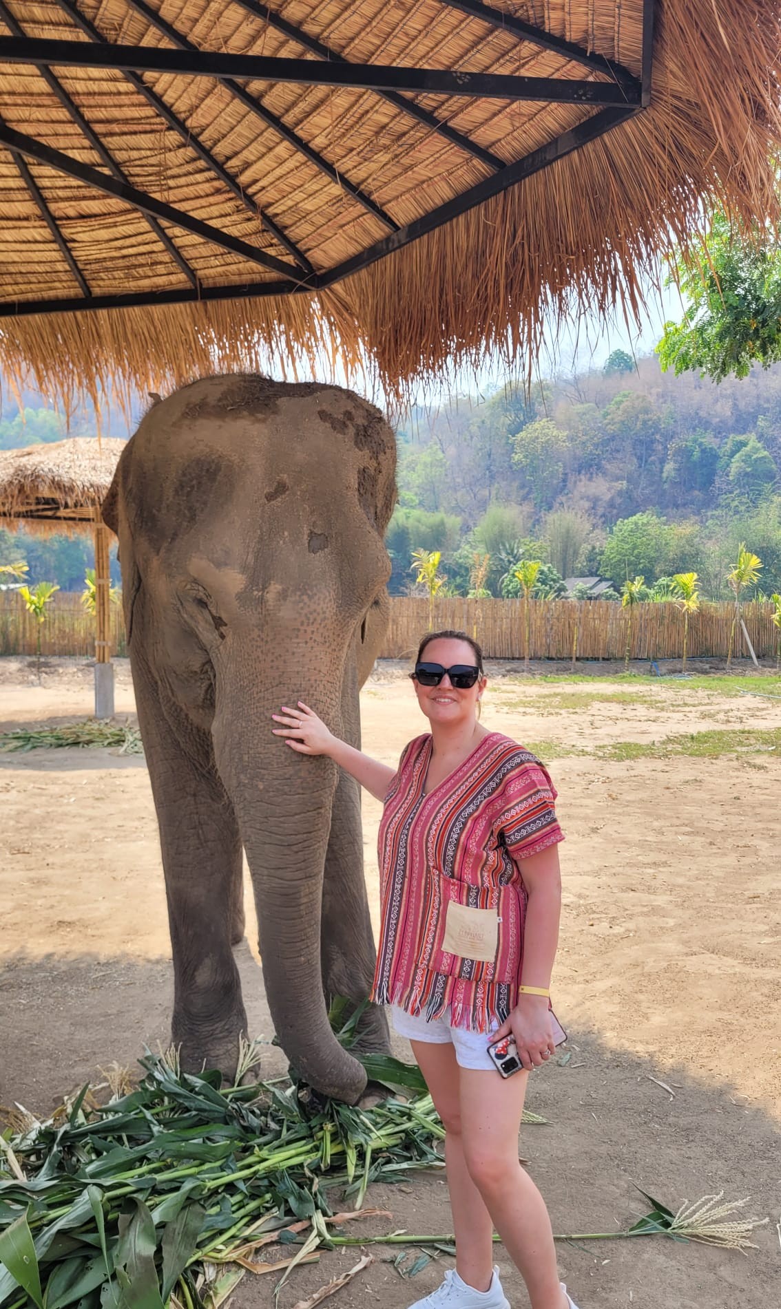 Leanne at an elephant sanctuary in Chiang Mai, standing in front of an elephant on a sunny day.