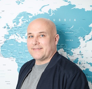 Matt in front of the office map, smiling for a profile-style photo.