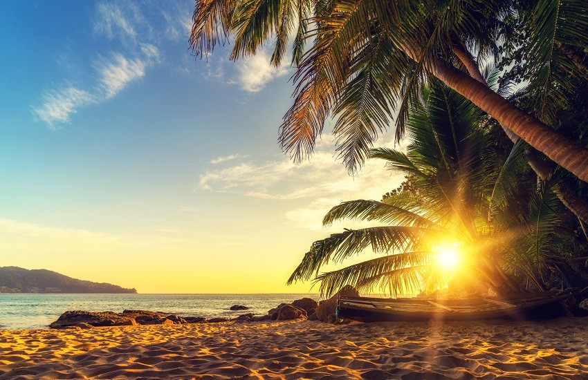 Sunset over Surin Beach Phuket with rowing boat and golden glow