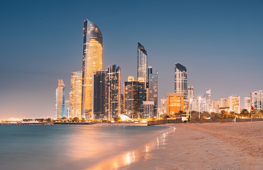 Stunning sandy beach near the Corniche in Abu Dhabi at night, with the city’s illuminated skyscrapers creating a striking backdrop.