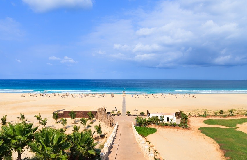 Boa Vista Beach with a wide stretch of sand and sea in the background, and a path leading to the beach passing by loungers.