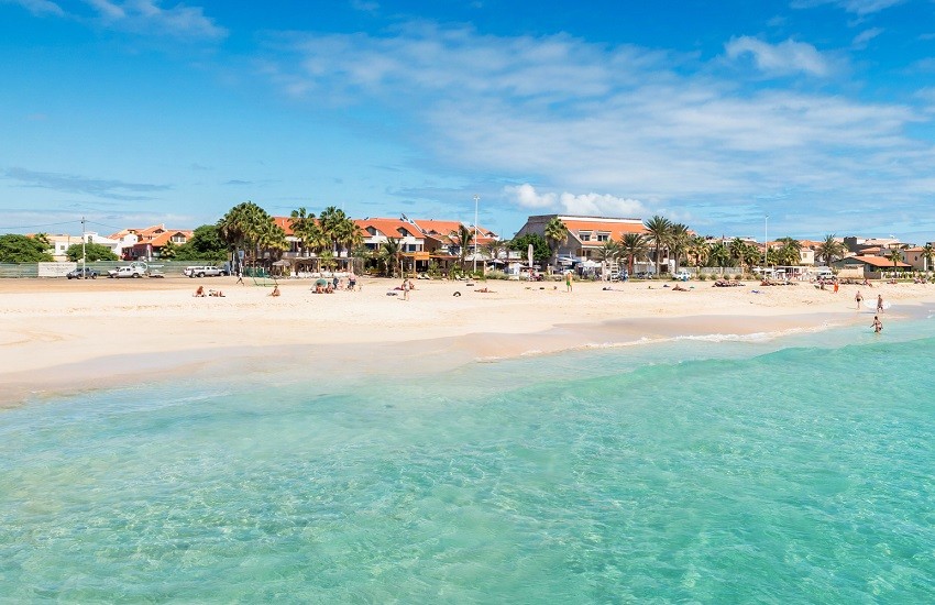 Panoramic view of Santa Maria Beach in Sal, Cape Verde, with white sands meeting clear blue waters in a quiet scene.