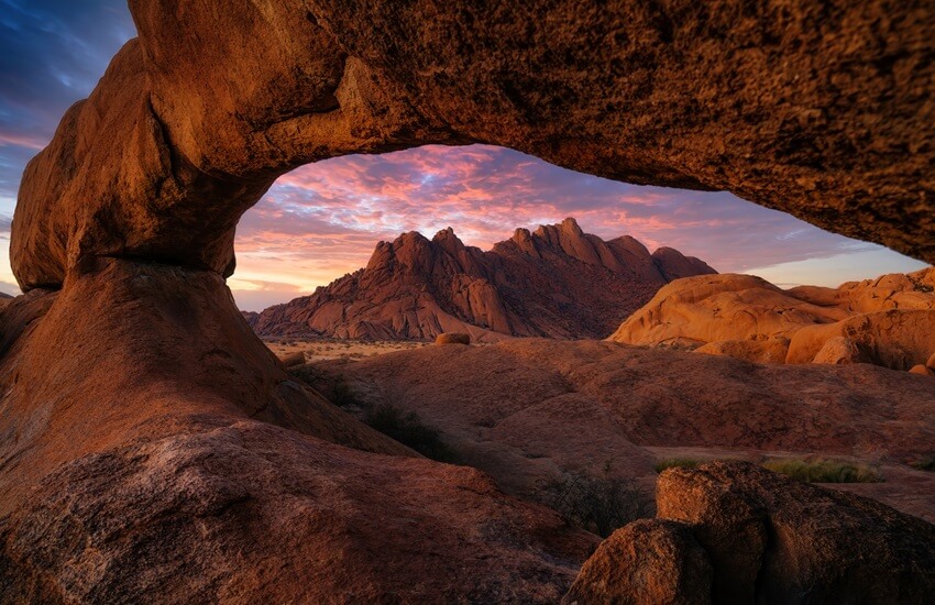 Red rock formations in Damaraland glowing under a dramatic pink and blue sky.