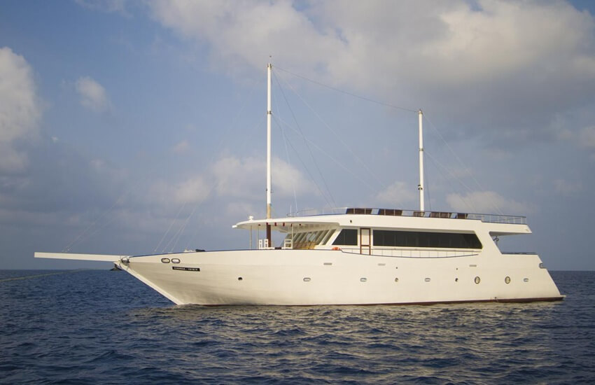 Traditional Maldivian dhoni boat converted into a small cruise ship sitting on calm turquoise waters
