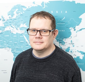 Profile photo of Rob standing in front of an office world map.